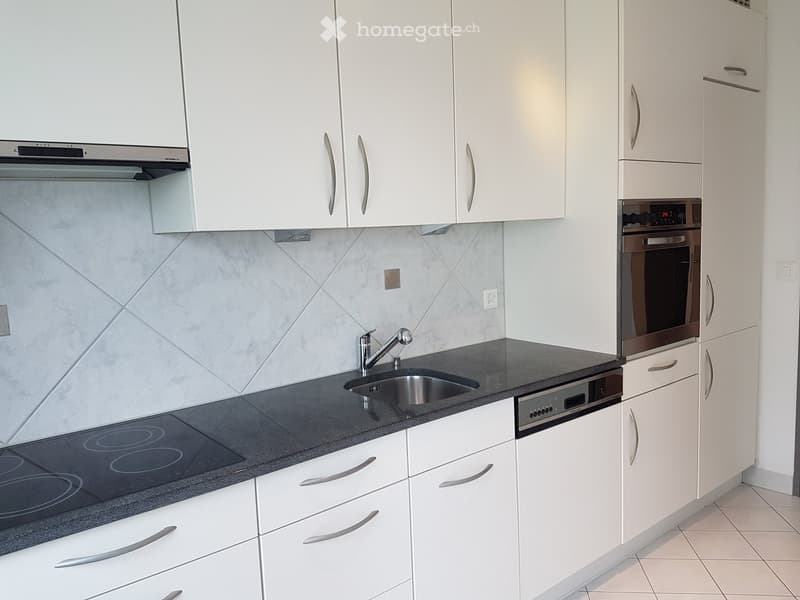 modern kitchen with white cabinets, black granite countertop, stainless steel sink, induction cooktop, built-in oven, dishwasher, and a faucet