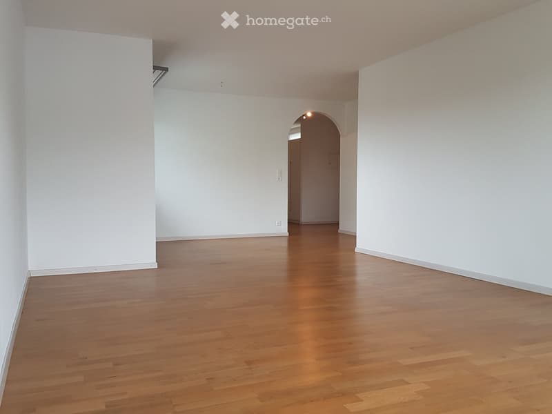 Empty room with wooden floors, white walls, and an arched doorway.