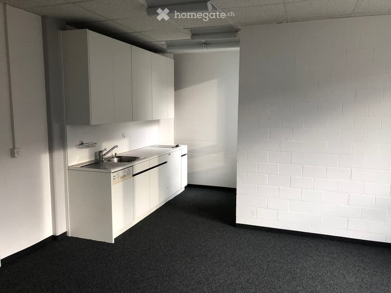 empty kitchen with white cabinets, stainless steel sink, floor to ceiling brick wall
