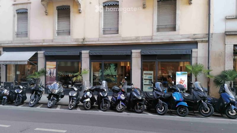 Exterior of a shop with motorcycles parked outside, three windows, black awnings