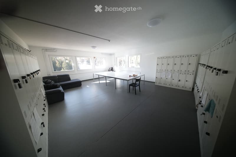 Empty room with a couch, table, chair, and lockers