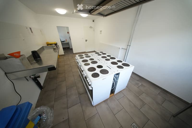 Empty kitchen with white appliances, tiled floor, stainless steel countertop, and a white oven.