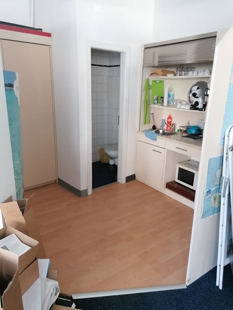 empty room, wooden floor, white walls, kitchen with sink and stove, toilet, cupboards, boxes