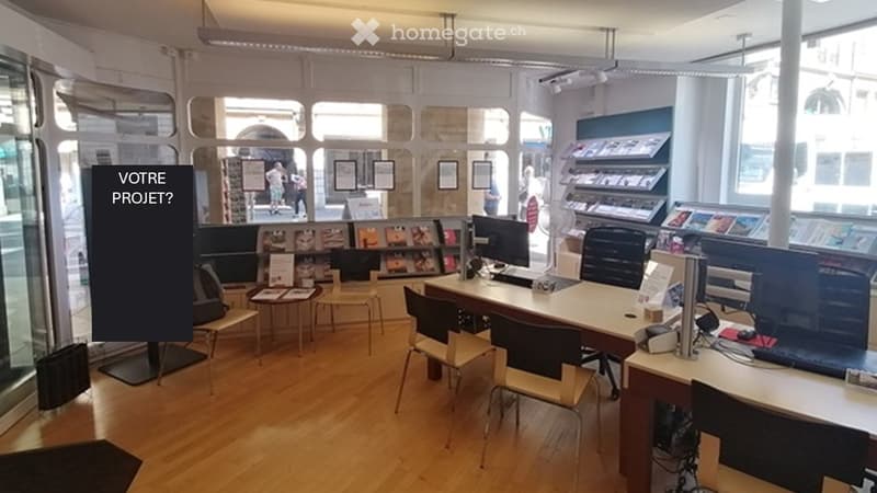 A modern office space with wooden floors, large windows, and a reception area.