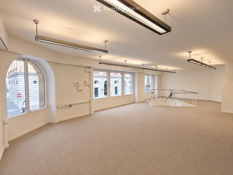 Empty room with beige carpet, white walls, large windows, and modern lighting fixtures.