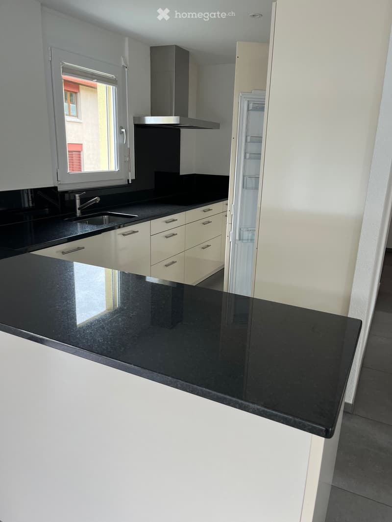 kitchen, black countertop, white cabinets, silver faucet, open fridge, range hood