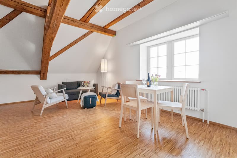 wooden floor, wooden beam ceiling, sofa, coffee table, radiator, window, table and chairs, wine bottle, glasses, flowers