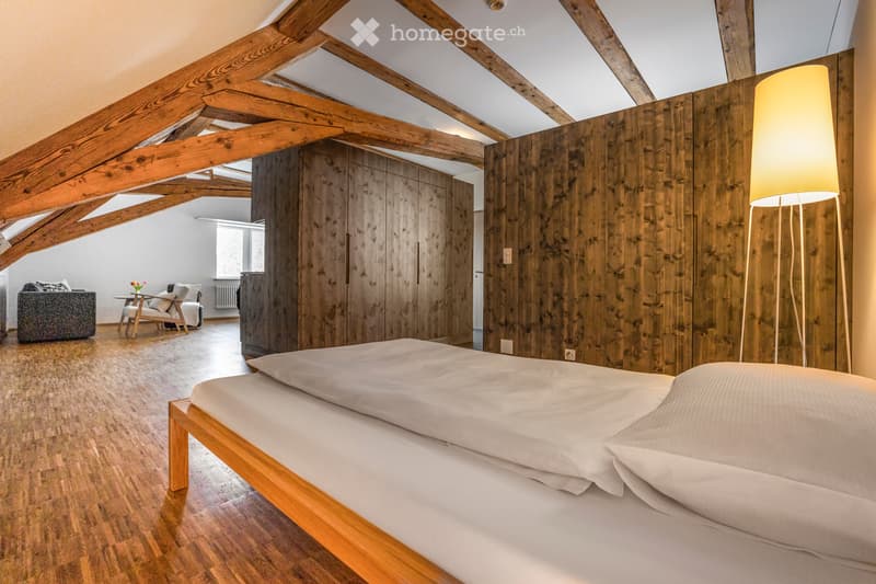 bedroom with wooden bed, wooden floors, wooden beams, wooden walls, two nightstands with lamps, wooden cabinet