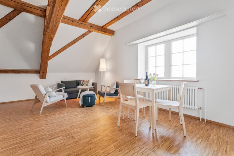 wooden floor, wooden beam ceiling, sofa, coffee table, radiator, window, table and chairs, wine bottle, glasses, flowers