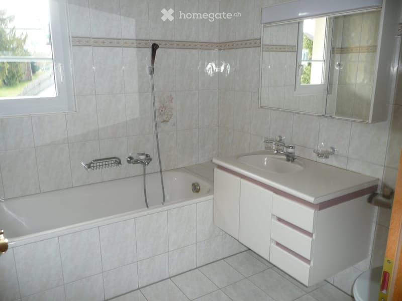 Modern bathroom with bathtub, sink, mirror, and white tiles