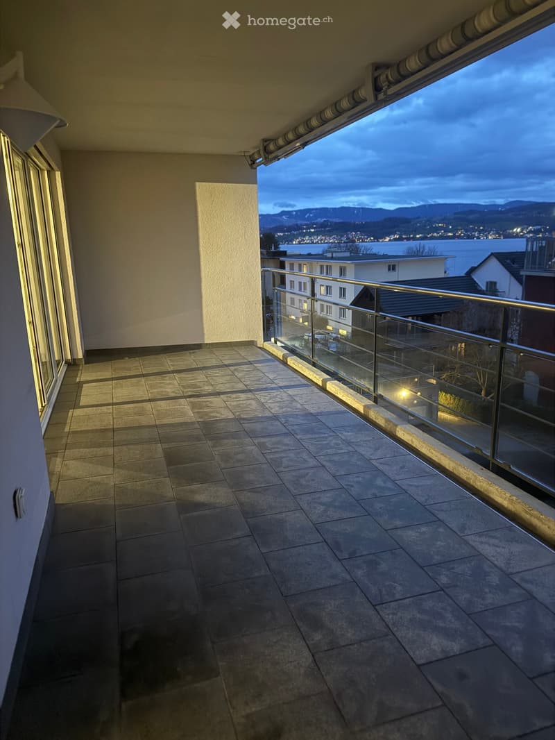balcony with tiles, railing, view of mountains and city lights, empty