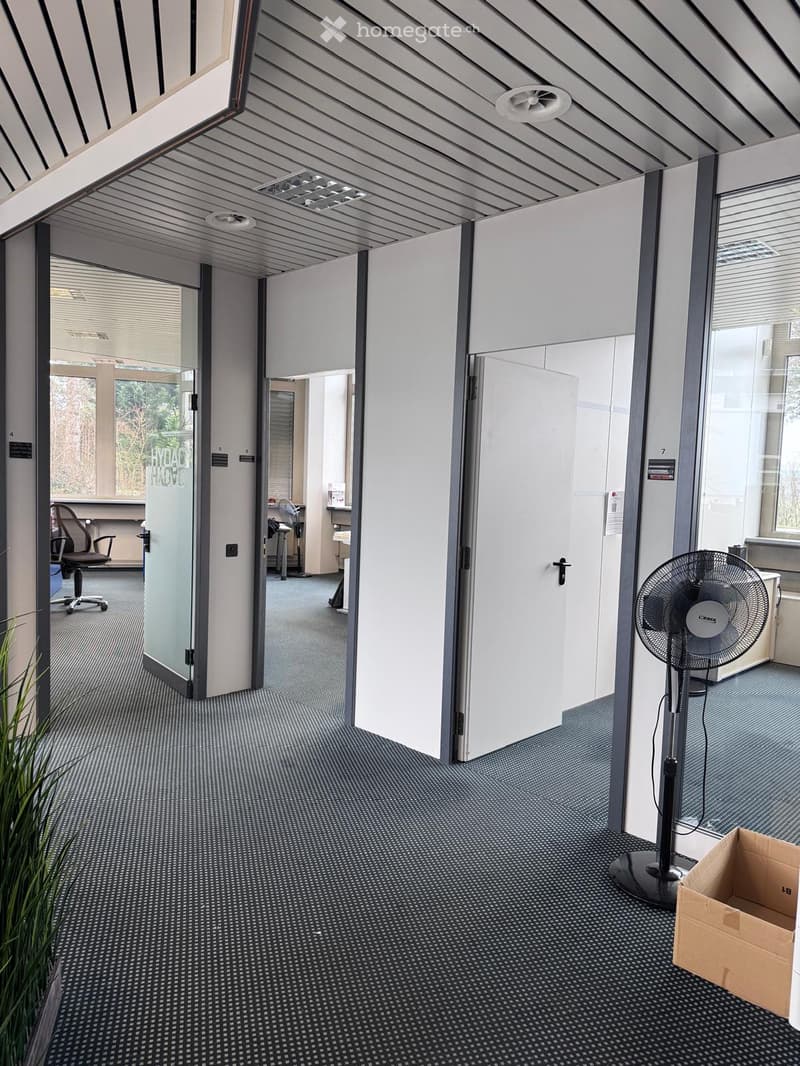 Empty office space, open doors, tiled floor, glass walls, ventilation grills, empty chair, office equipment, glass doors, box, fan.