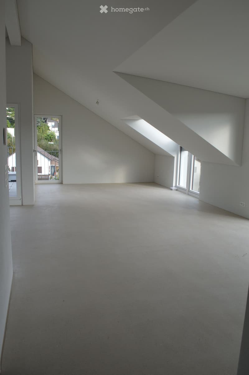 Empty attic room with three windows and glass door.