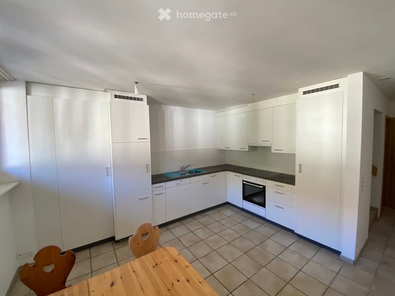 Kitchen with white cabinets, granite countertops, stainless steel sink, oven, tiled floor, and wooden dining table