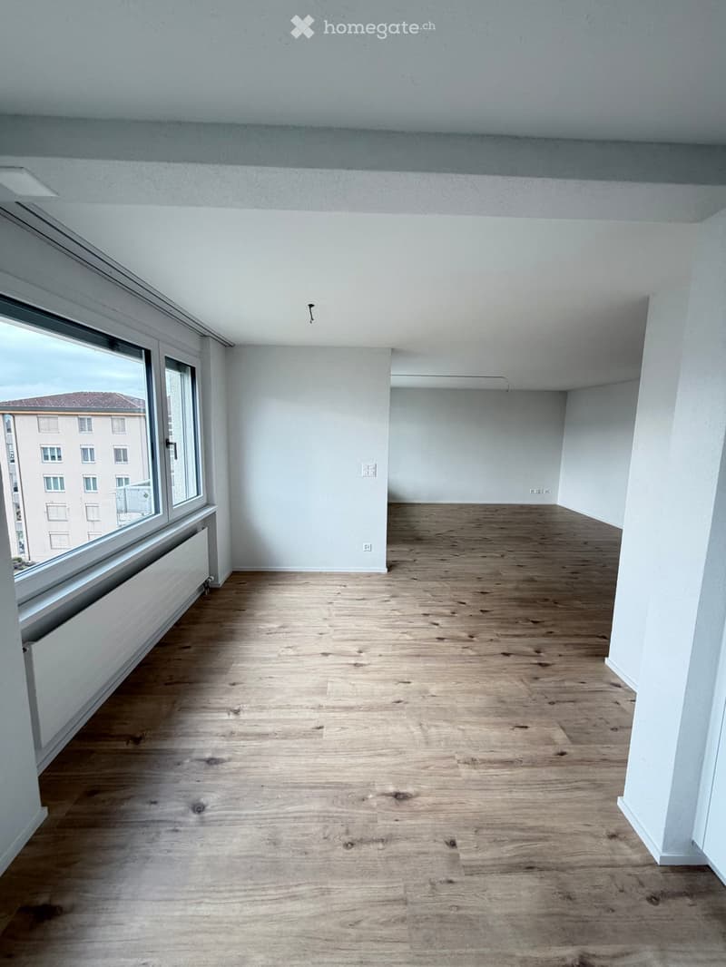 empty room with windows, wooden floor, white walls, radiators