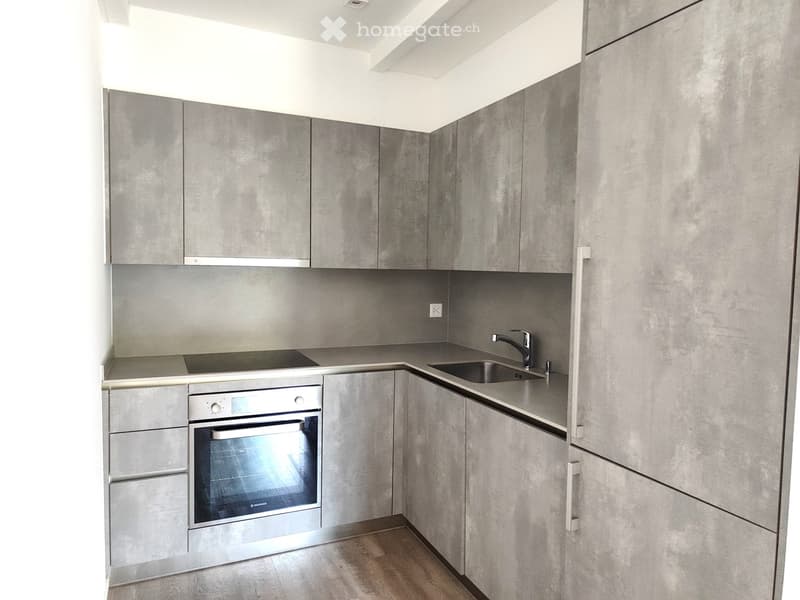Modern kitchen with grey cabinets, stainless steel oven, sink, and faucet.
