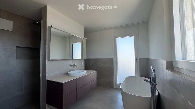 modern bathroom with white bathtub, large vanity, glass door, tiled floor