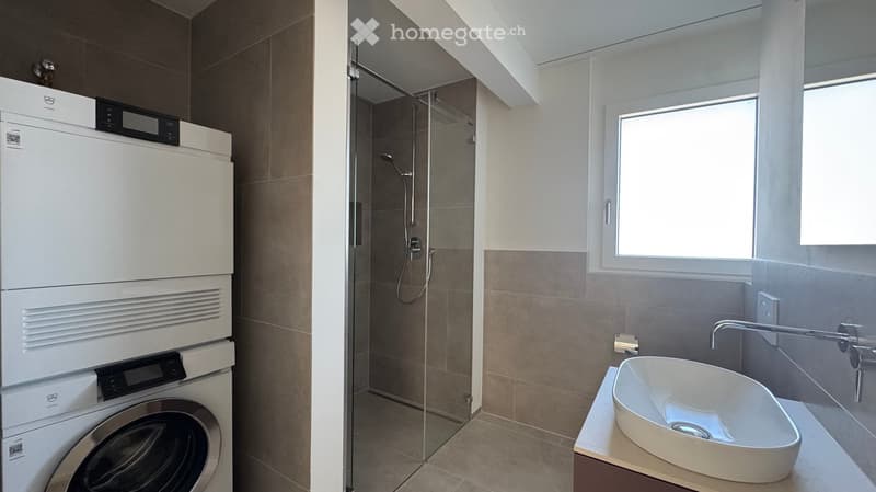 small bathroom with washer, dryer, glass shower, sink, window
