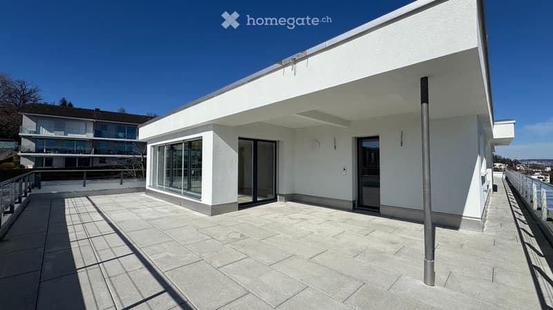 modern, white building with large windows, tiled terrace, black railings, panoramic views