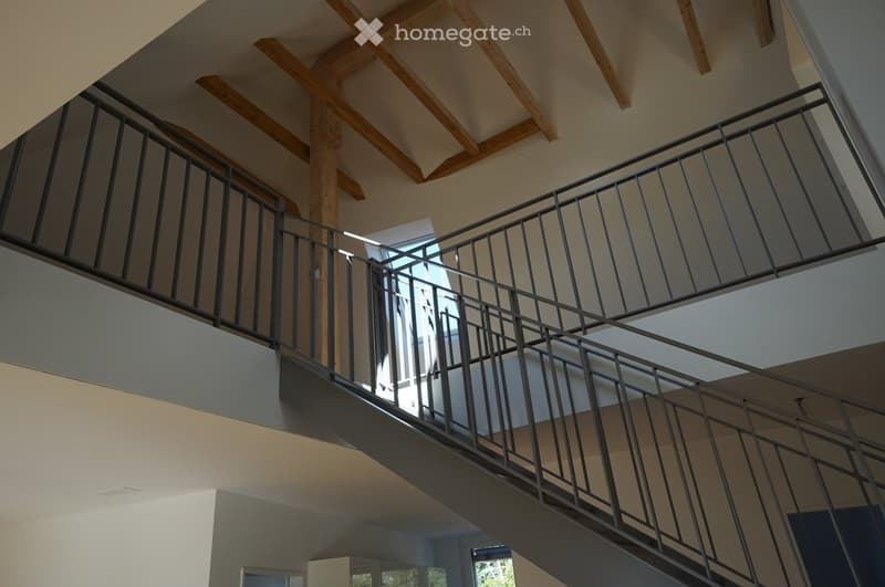 steel staircase railing, wooden ceiling beams, open staircase landing with a skylight
