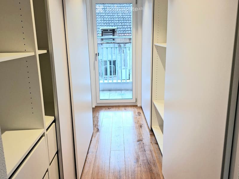wooden floor, hallway leading to a balcony with glass door and metal railing