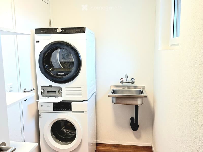 Stacked washing machine and dryer, stainless steel sink, mounted pipes, cabinets