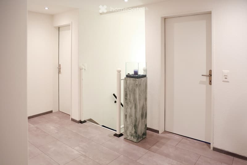 Staircase to upper floor, tiled floor, white walls, decorative pillar, light switch, white doors