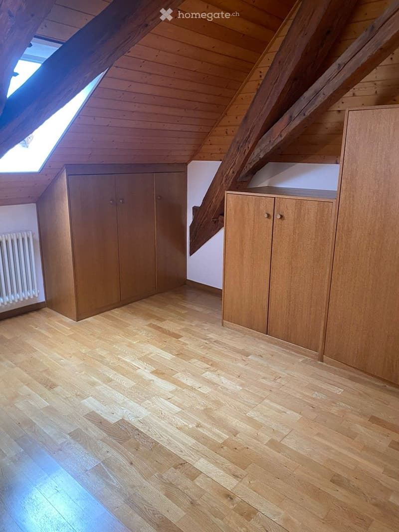 wooden floors, white walls, wooden beams, three wooden cupboards, small white radiator
