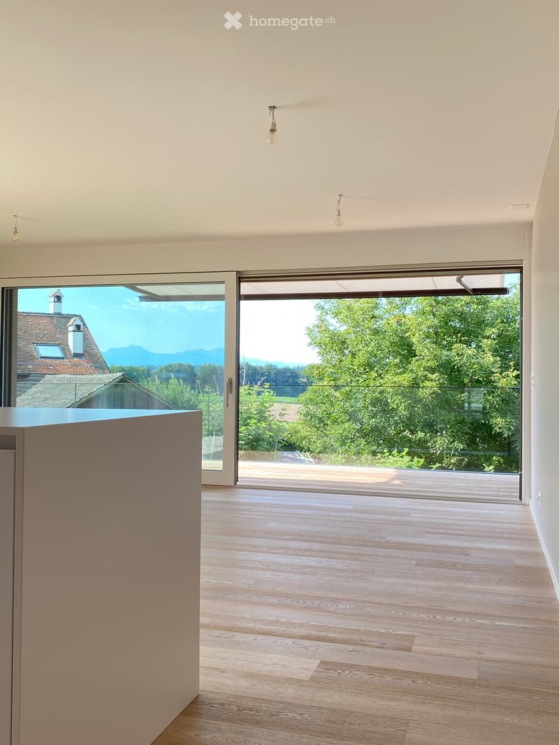 large windows, wooden floor, open sliding doors to balcony, view of mountains