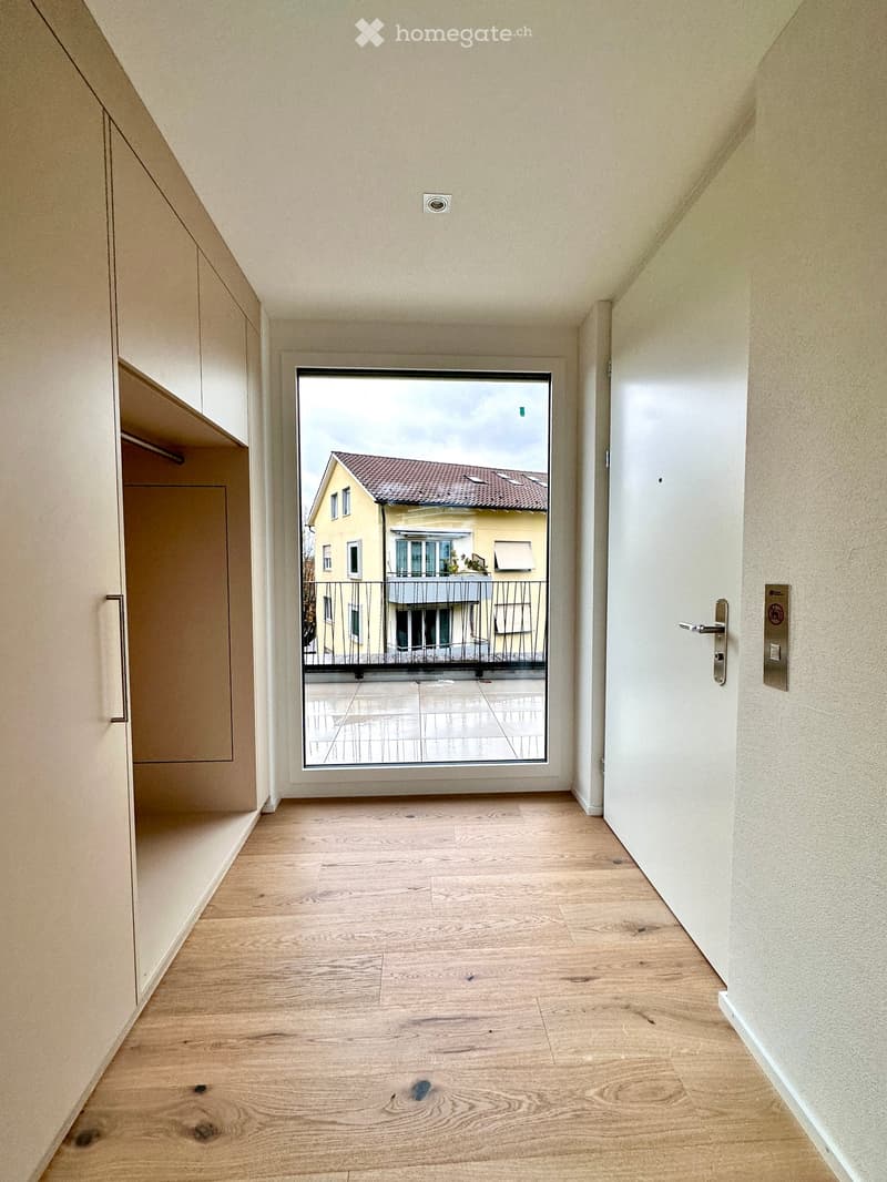 Empty hallway with wooden floor, glass door, and a balcony view