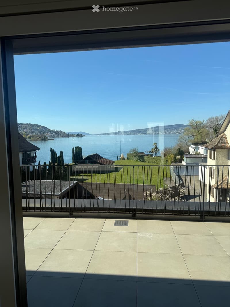 Balcony with railings, tiled floor, view of a lake and mountains