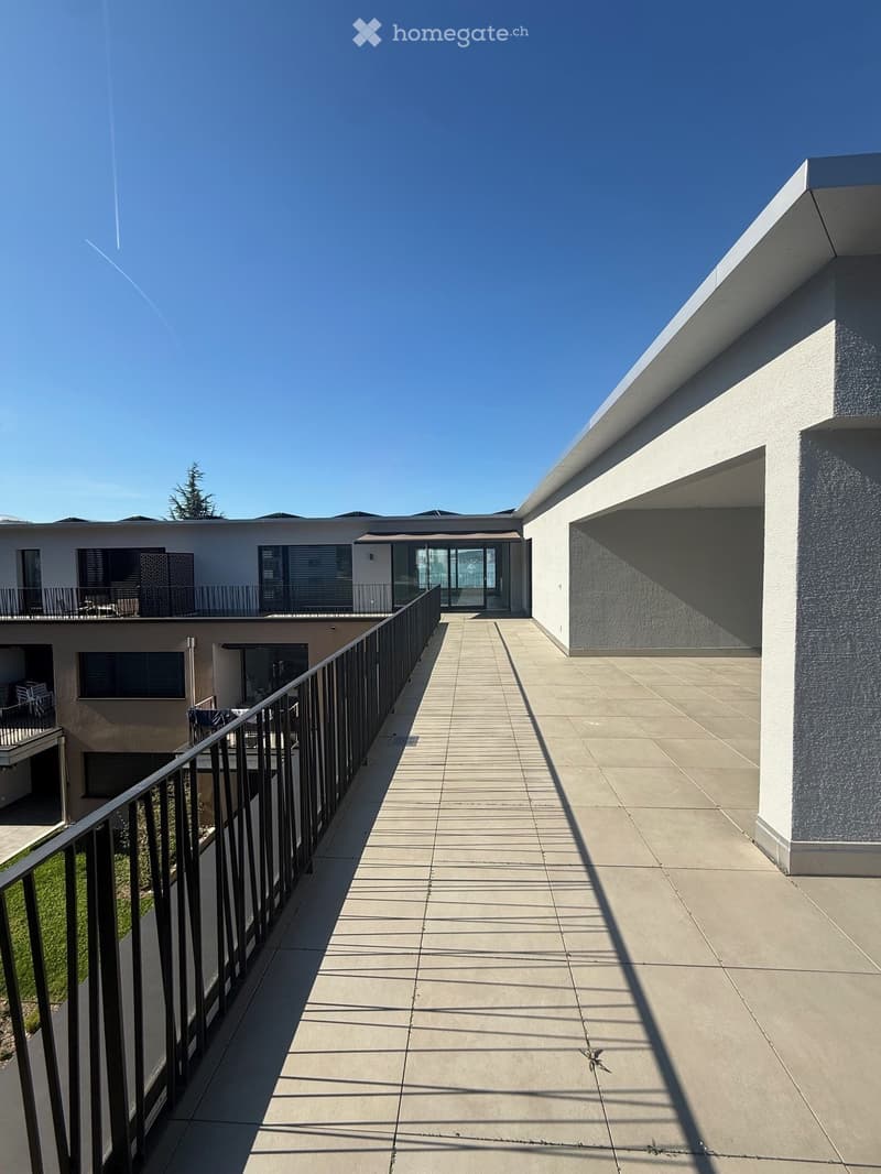 modern building, balcony, tiled floor, black railings, glass doors, clear sky