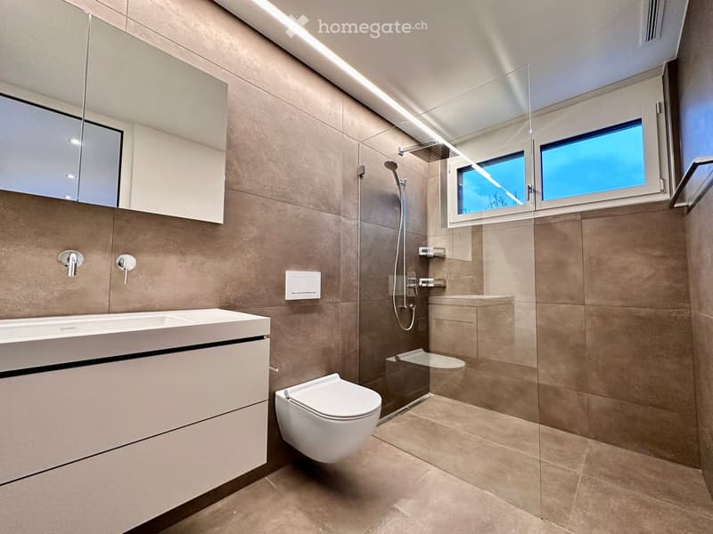modern bathroom with white sink, white toilet, glass shower, beige tiles, mirror, faucet