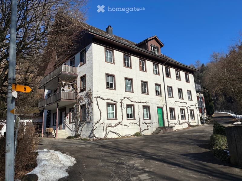 3 story building, white wall, brown trim, balcony, green door, brown roof