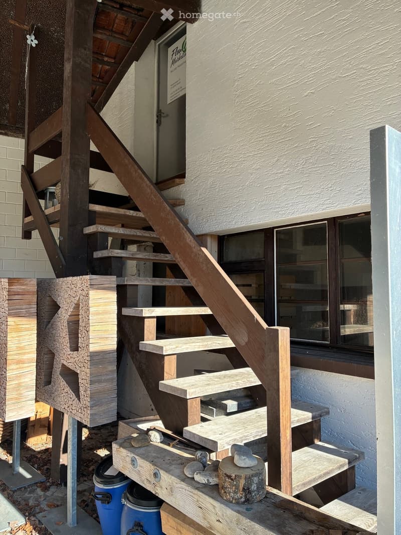 outside wooden stairs, raised ground floor, grey door, windows, white brick wall
