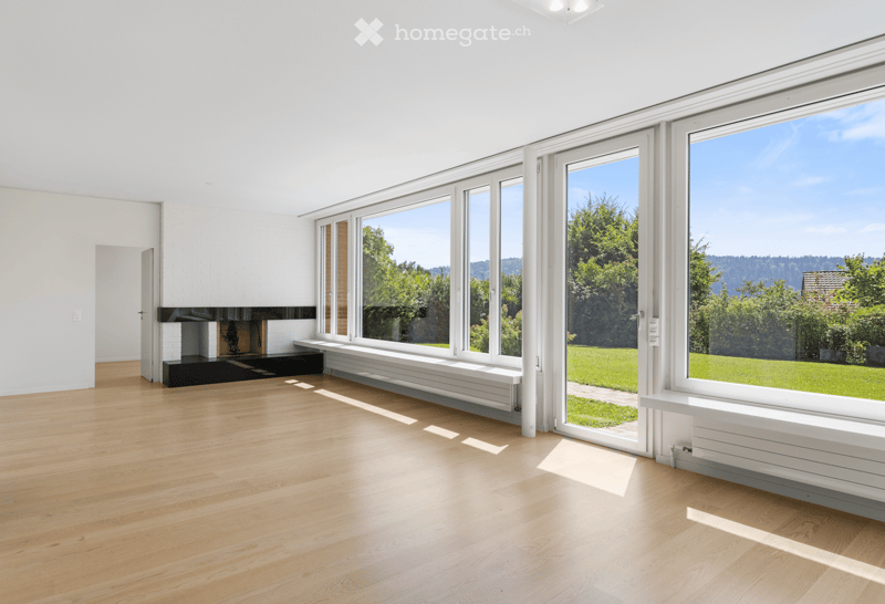 living room with a fireplace, large windows, wooden floor, white walls, view of the outside