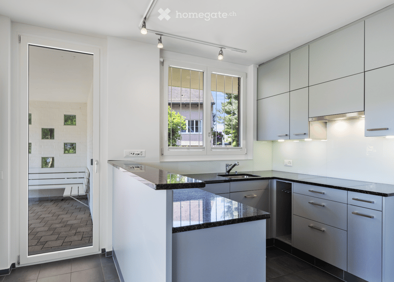 modern kitchen with island, granite countertop, stainless steel faucet, white cabinets, glass door to outdoor area