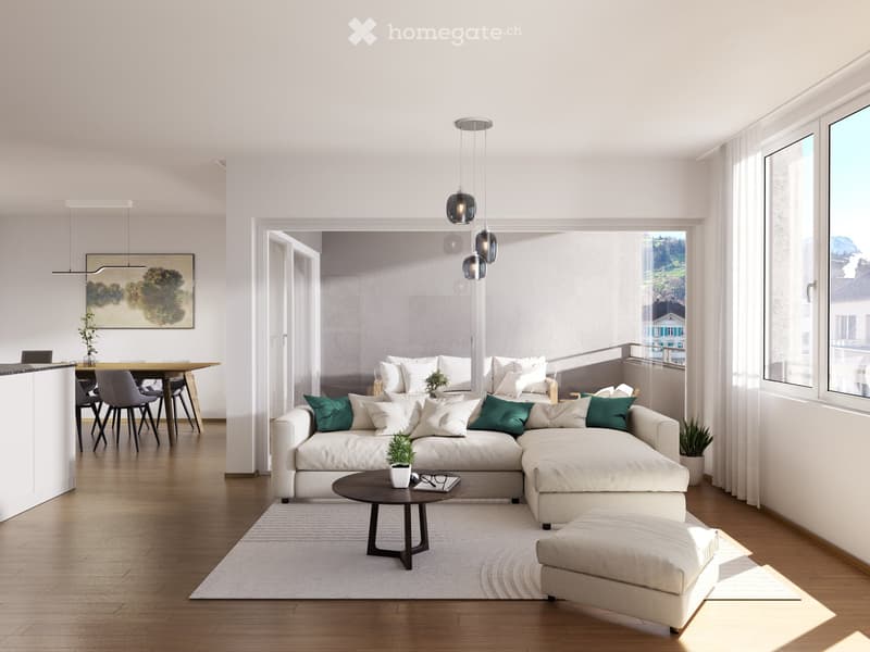 Modern, open-plan living room with large windows, balcony, sectional sofa, hardwood floors, pendant lights, round coffee table, neutral color scheme, and a view of the surrounding landscape.