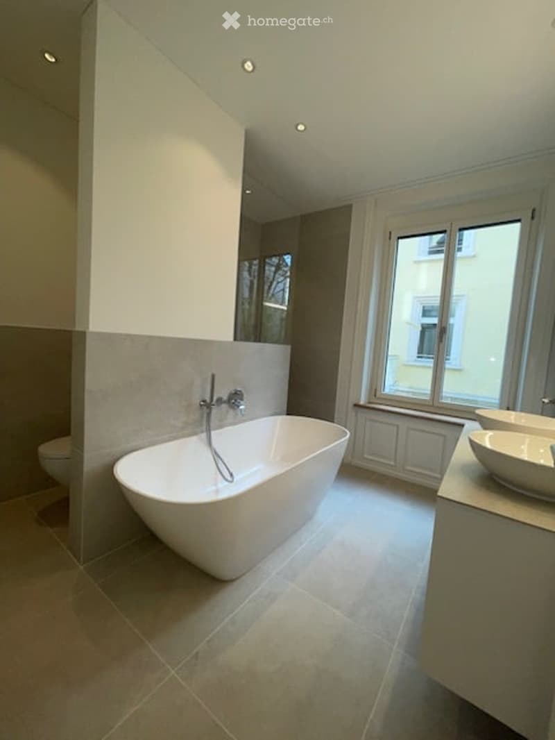 modern bathroom with bathtub, two sinks, toilet, large window