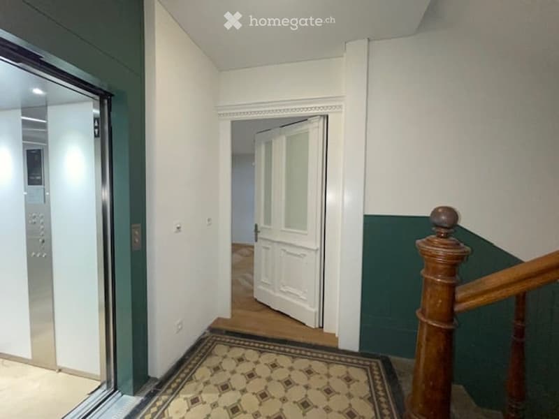 elevator, wooden handrail, tiled floor, white walls, wooden floor