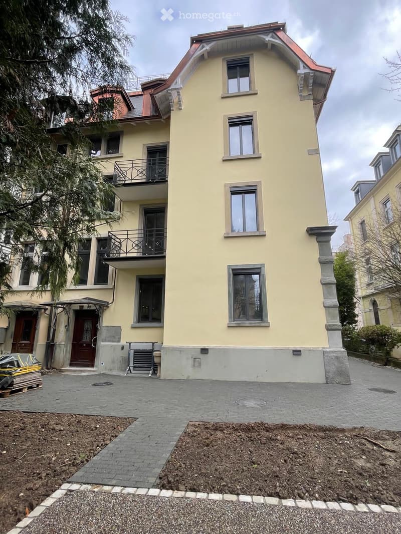 3 story yellow house, several windows, balcony, 2 doors