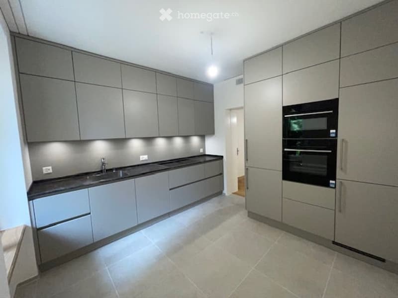 modern kitchen with gray cabinets, black countertops, double oven, sink, faucet, tiled floor