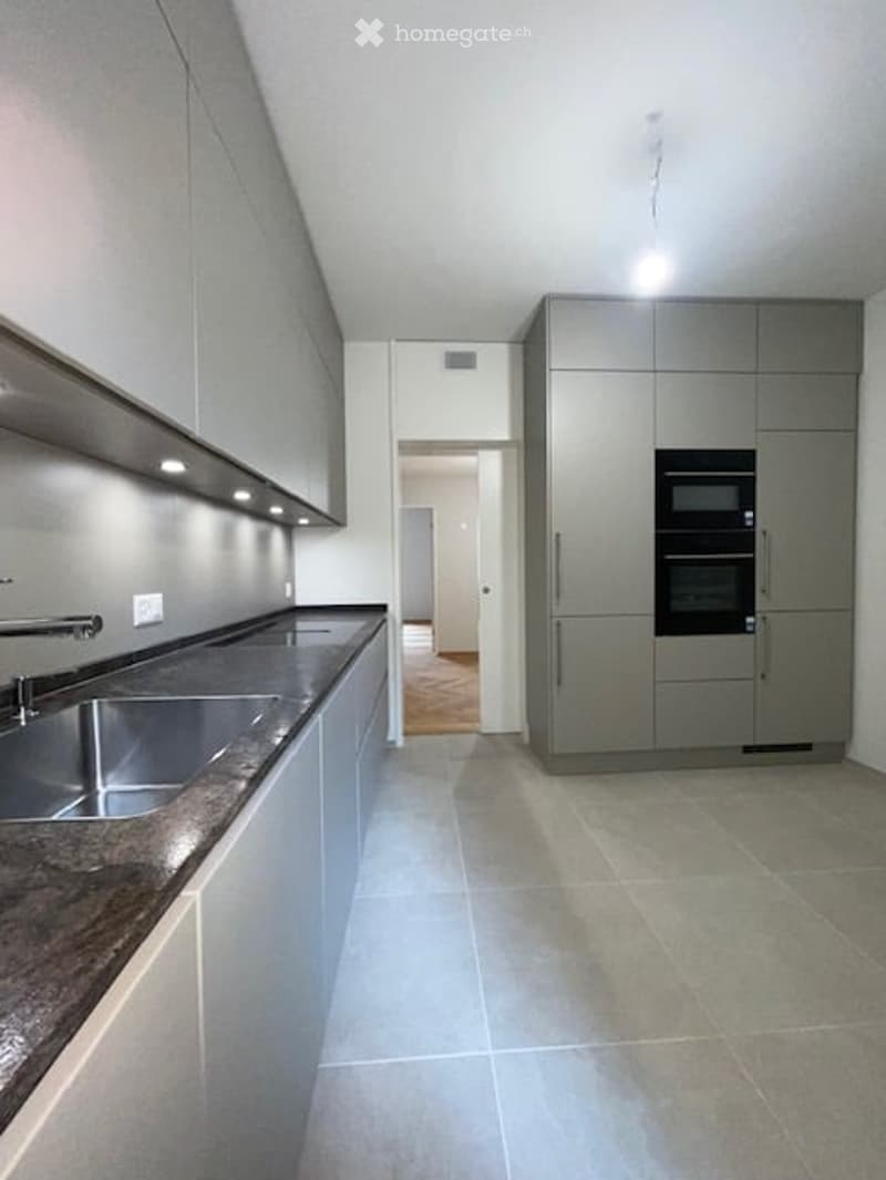 modern kitchen with gray cabinets, granite countertop, stainless steel sink, double oven, wooden floor