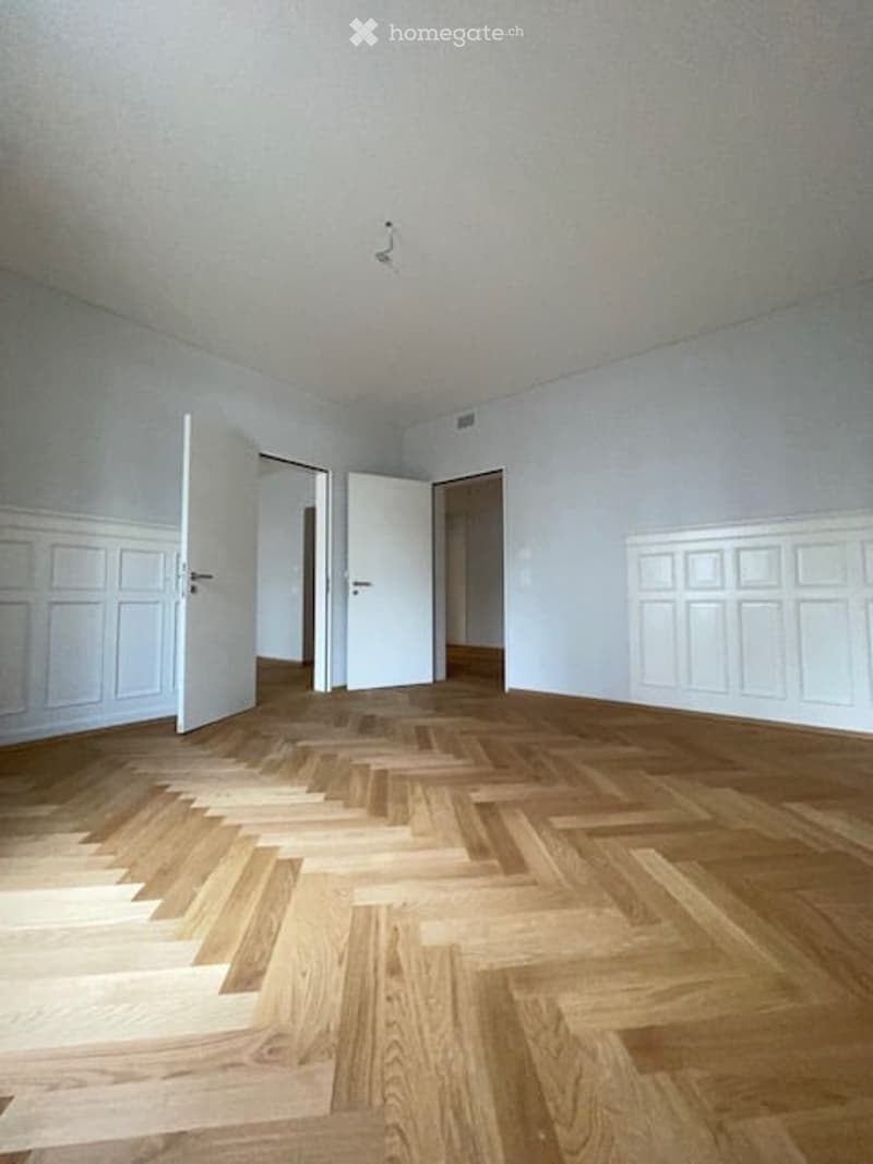 empty room, wooden parquet floor, white walls, white doors, wooden paneling on walls
