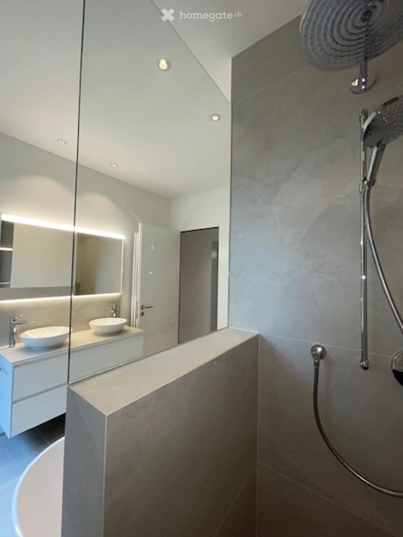 modern bathroom with large mirror, two sinks, bathtub, shower, and a glass partition