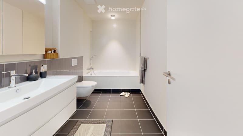 modern bathroom, white bathtub, white sink, toilet, towels, black tiled floor