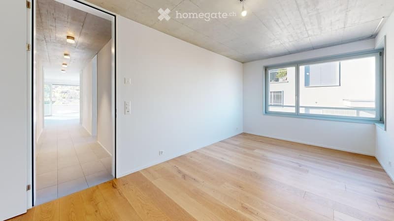 Empty room with wooden floors, white walls, and large windows.
