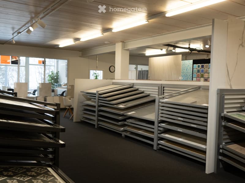 interior of showroom with light fixtures, racks of materials, chairs, tables, clock
