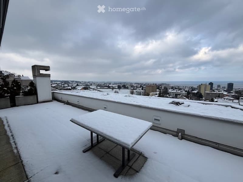 table on terrace, snow on ground, distant city view