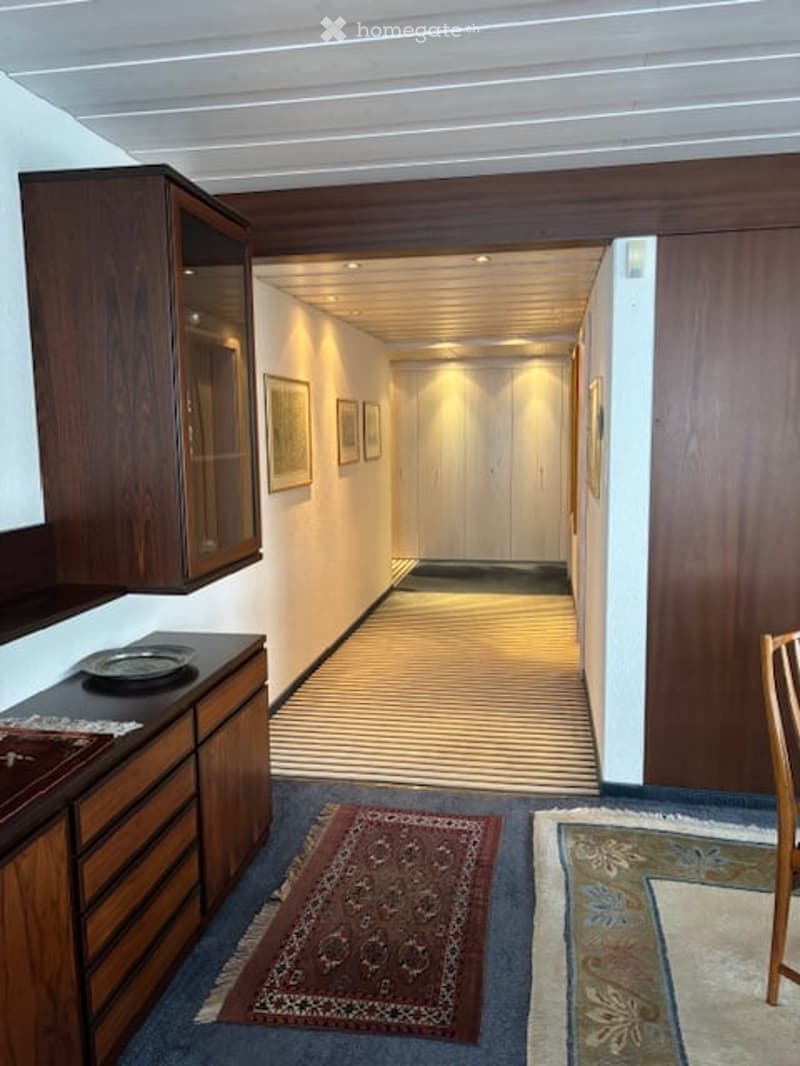 dark wood walls, striped hallway, dark brown hardwood floor, brown wood counter, brown wood cabinets, small dining table, 2 oriental rugs